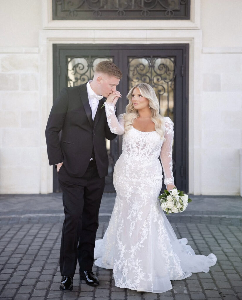 Groom kissing his bride's hand in front of The Estate at Florentine Gardens, a luxury wedding venue near Jersey City.