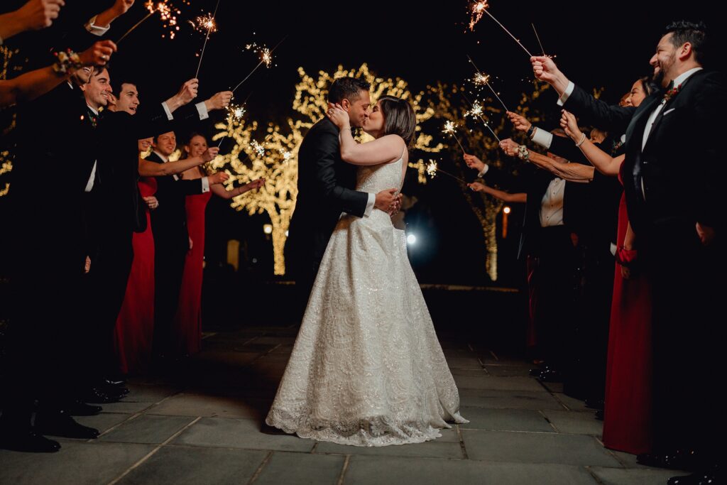 Couple kissing after their wedding with sparklers around them.